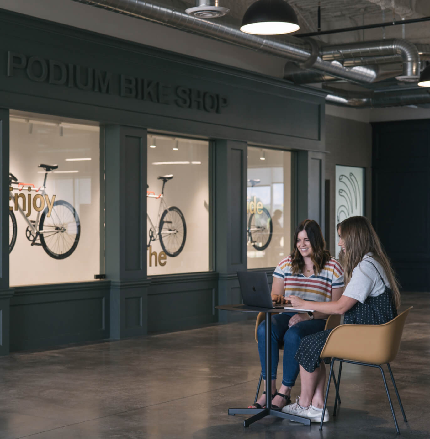 rachel and alex sitting by the podium bike wall