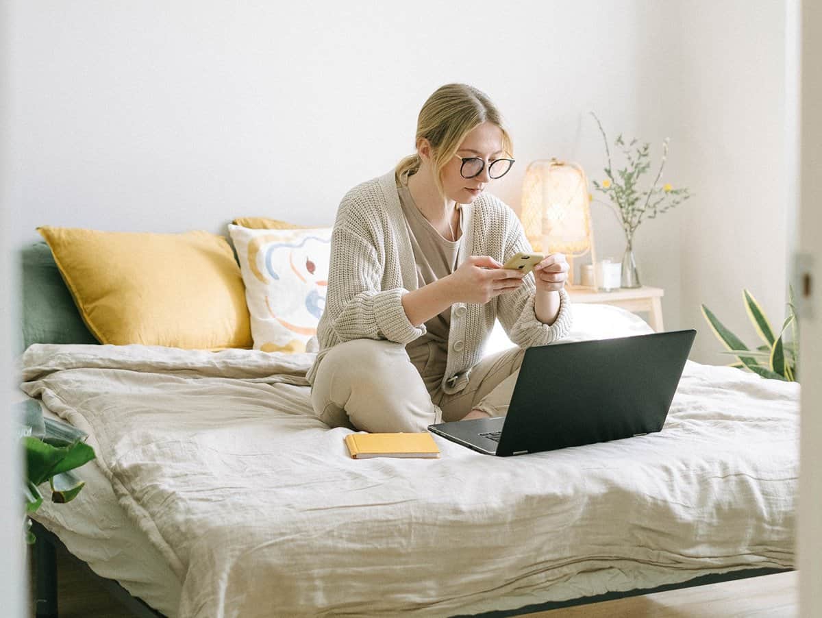 woman sitting on bed sending text from a computer