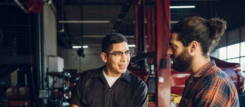 Auto shop repairman speaking with client