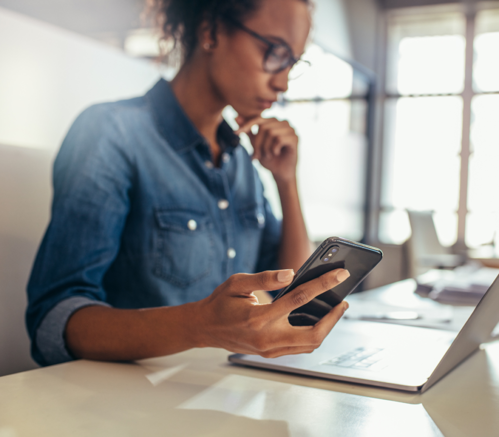 woman looking at phone and computer